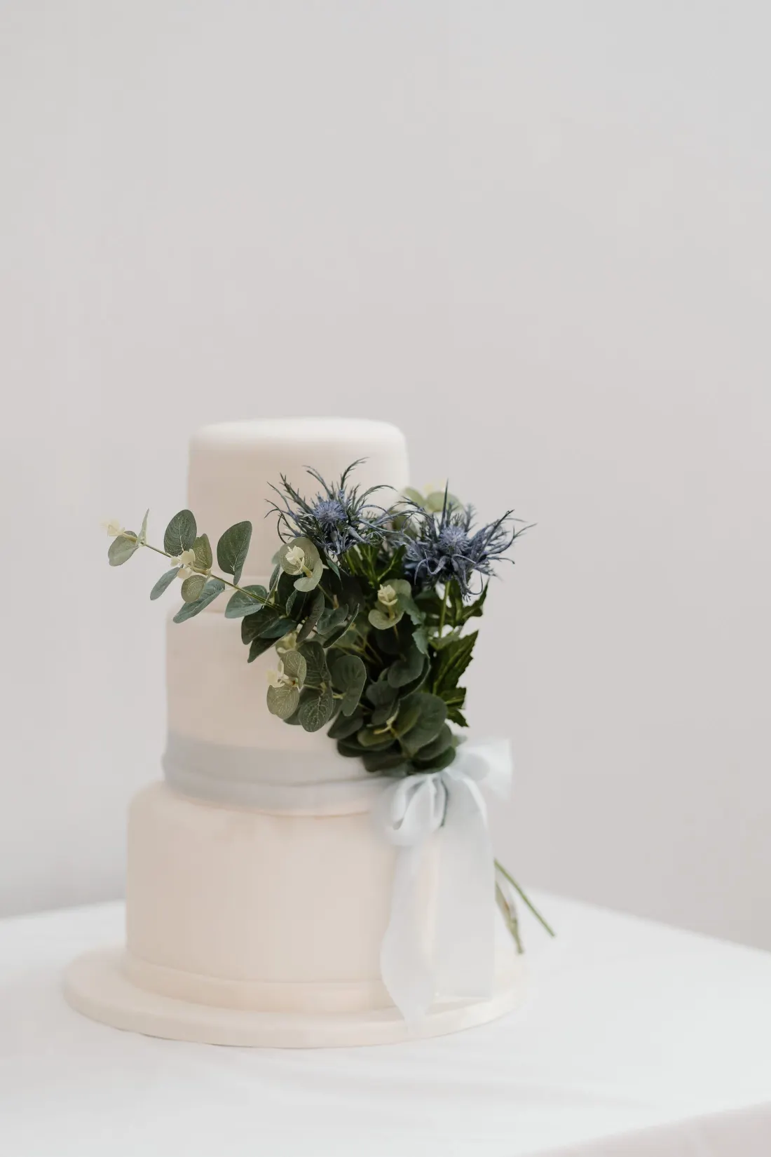Pièce montée blanche à deux étages décorée d’eucalyptus